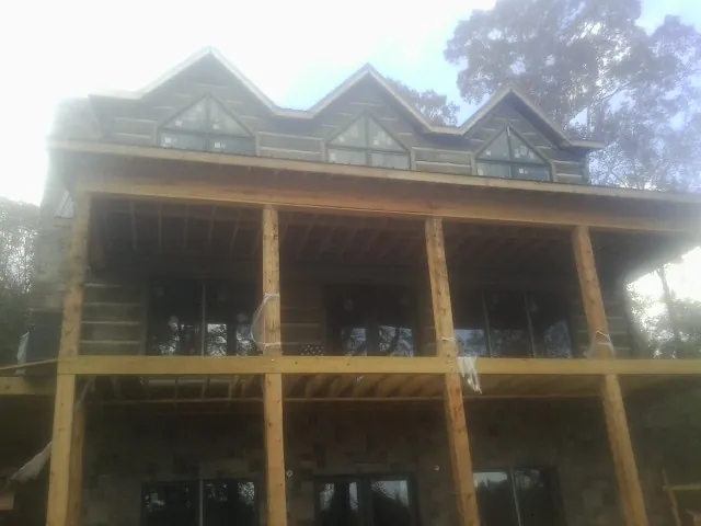 Dormers and porch framing on a large log home under construction — Roof Coating work by our crew in Marcellus