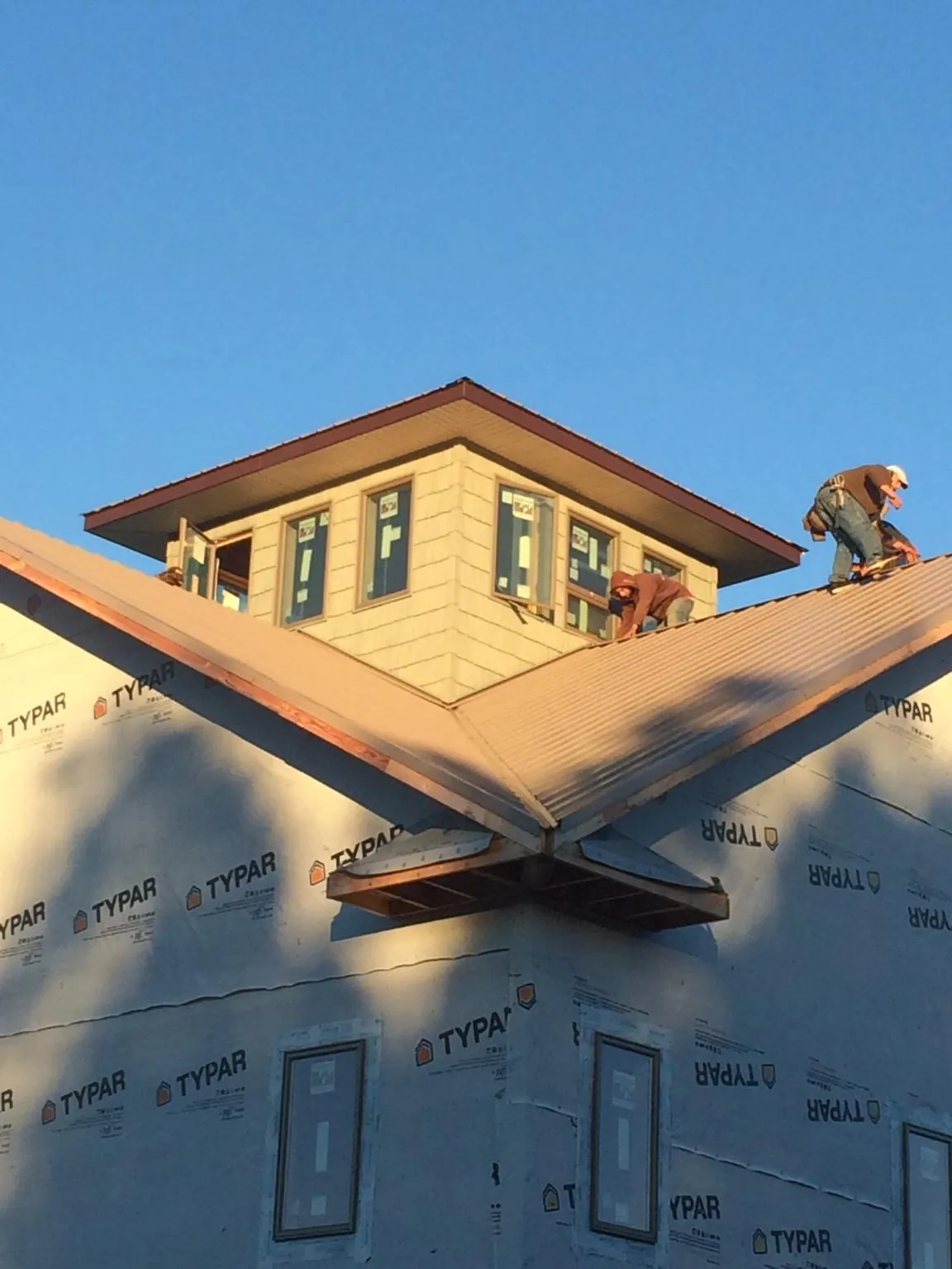 Roofers working around a rooftop cupola on a new metal roof at sunset — Roof Waterproofing in Marcellus by Roofing Brothers